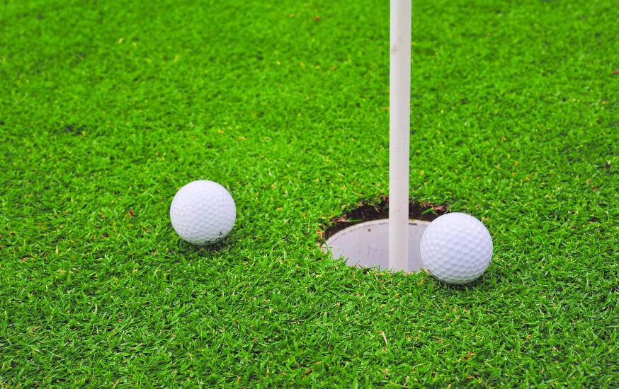 Two golf balls on golf course putting green